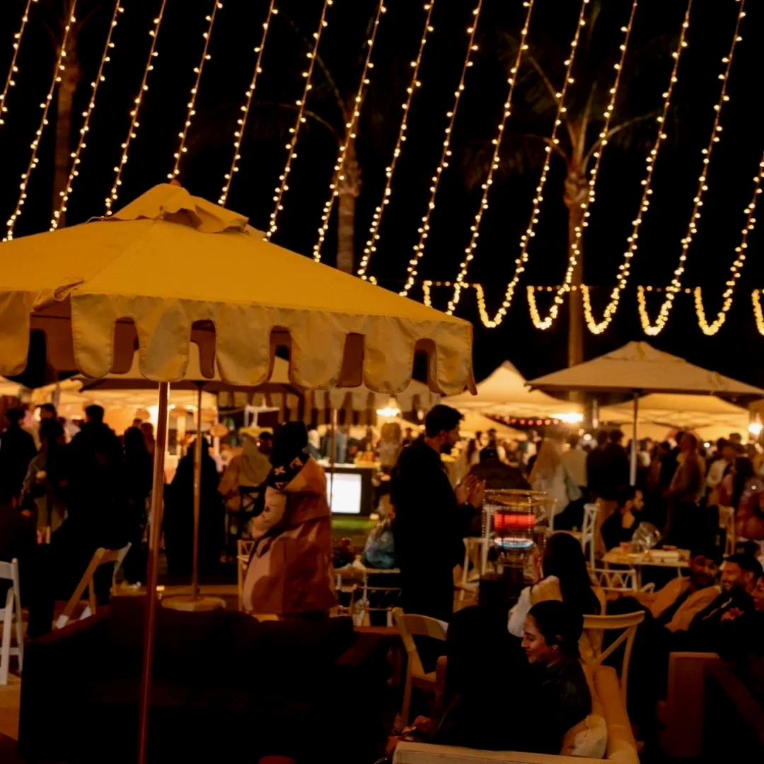 A marquee at night beneath a dense canopy of warm fairy lights
