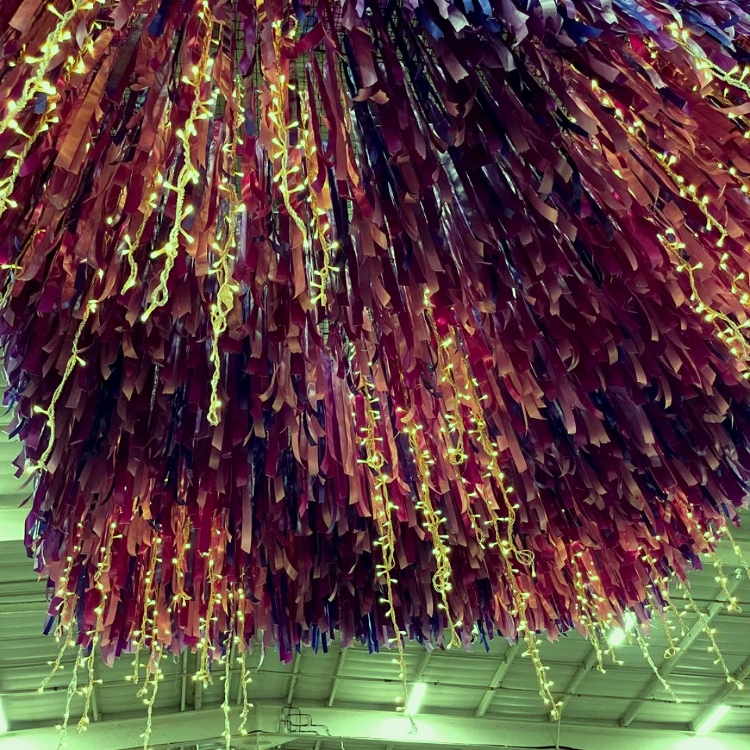 A dense magenta and purple tinsel chandelier lit from within