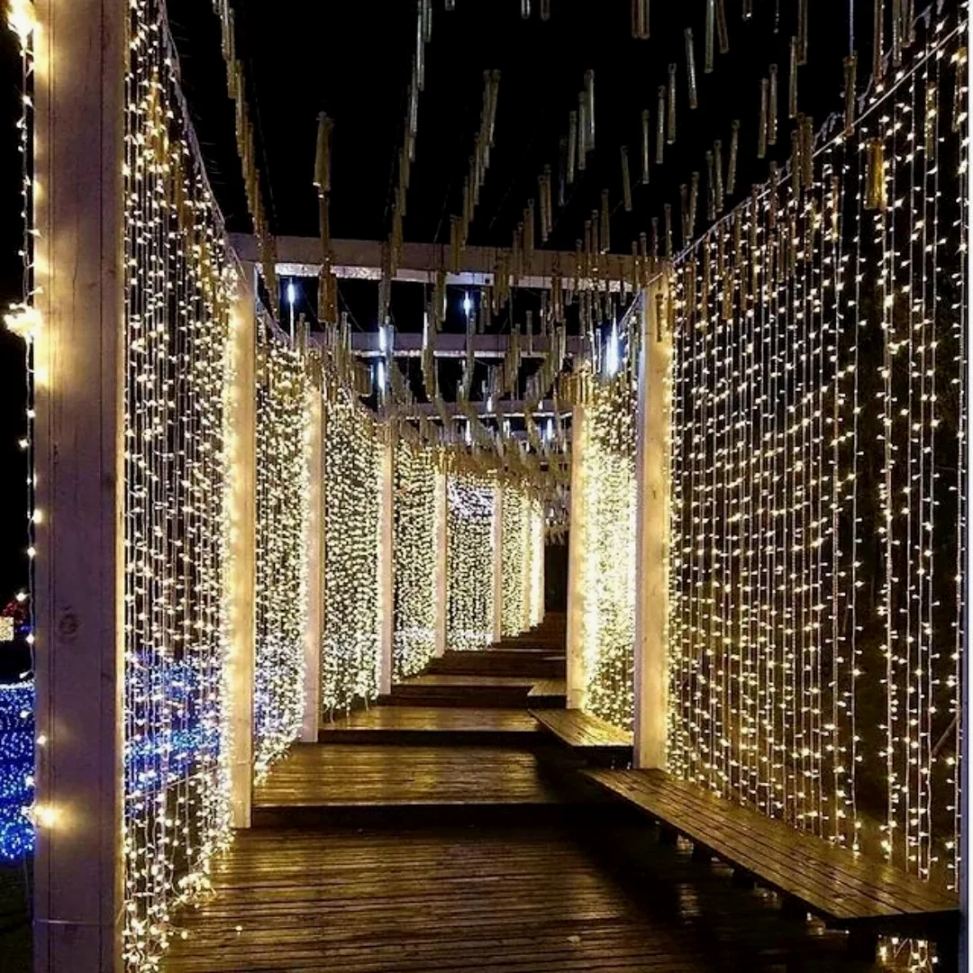 A walkway lined with floor-to-ceiling curtains of warm fairy lights