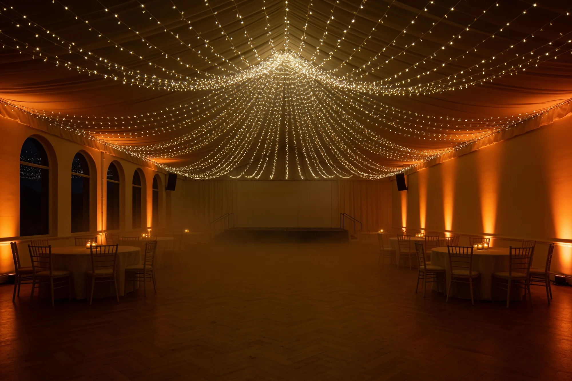 The same hall dressed with a fairy-light canopy radiating across the full ceiling