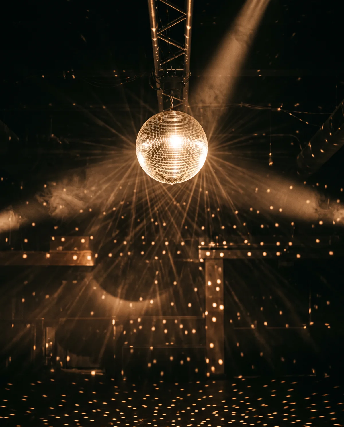 A mirror ball scattering points of warm light through haze